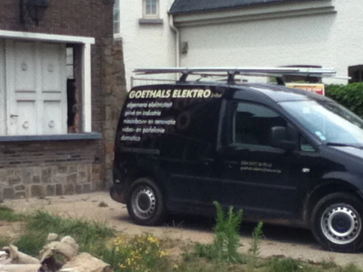 a black van parked next to a white brick building