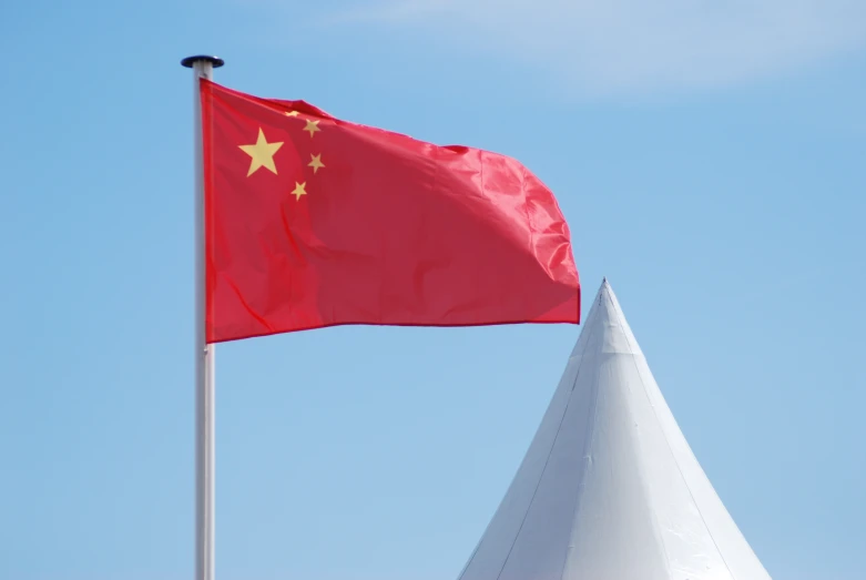 the flag of china is being waved on top of the buliding