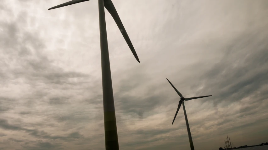 two wind turbines on a beach with some storm clouds