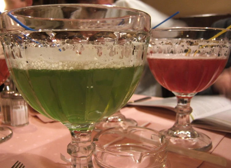 two glasses filled with different kinds of drinks on a table