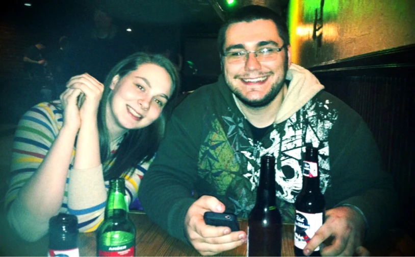 the man and woman are smiling while sitting at the bar