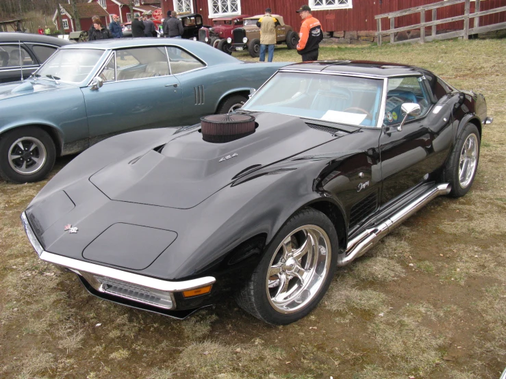 a dark colored corvette car sits parked by other cars