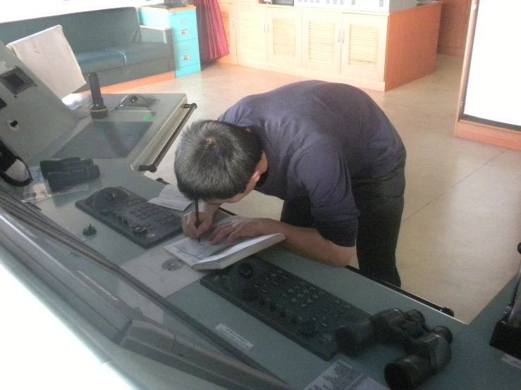 a man is writing at a desk in front of a computer