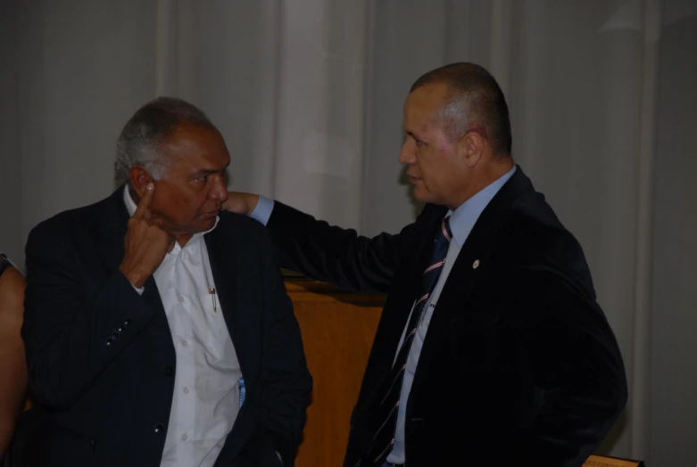 two men standing next to each other in front of a screen