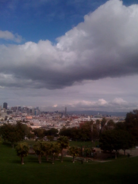 some tall buildings under a gray and white cloud filled sky