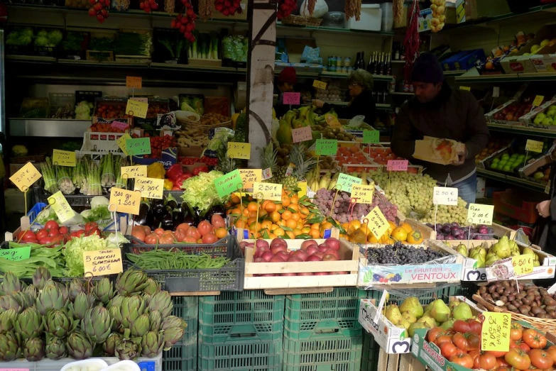 a fruit stand with fruits for sale and people