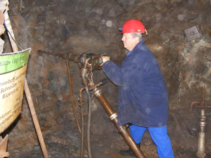 a man in blue jacket working on a pipe