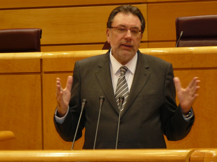 a man standing behind a podium and gesturing