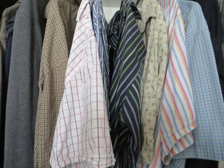 several shirts and ties on hangers in front of a window