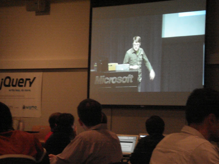 people sitting at tables in front of a projector