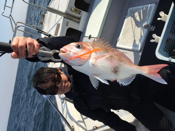 the person holds the fish he caught off the boat