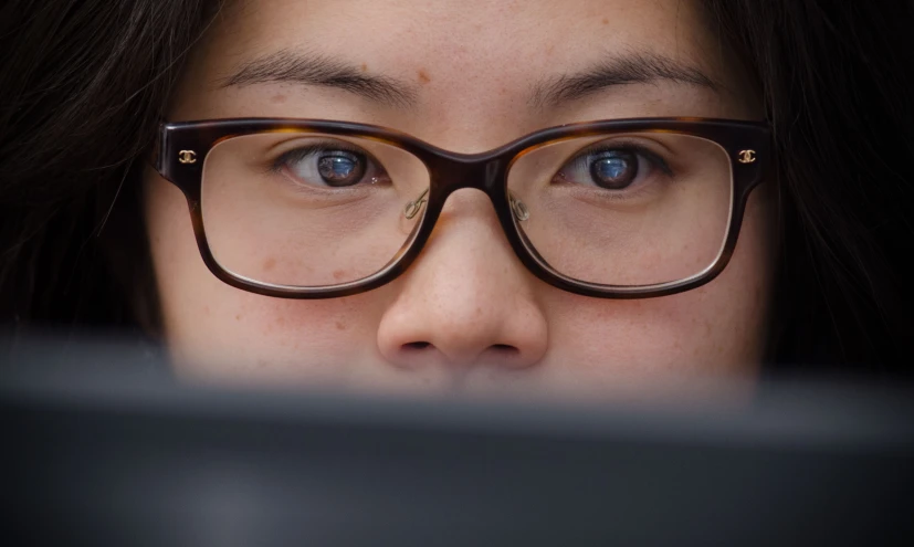 woman wearing glasses looking at a computer monitor