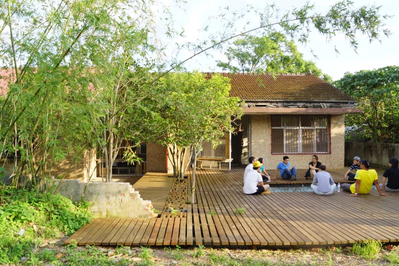 several people sitting on a wood deck near trees