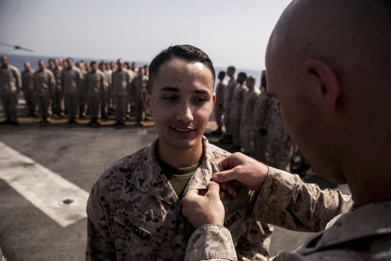 a soldier is adjusting a tie on another man