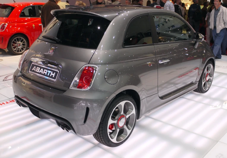 a small gray car is on display in a show room