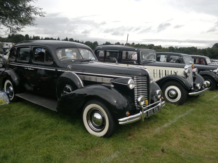 a row of parked antique cars sitting in grass