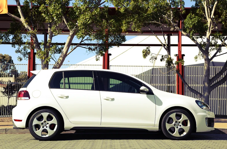 a white car with grey rims parked in a parking lot