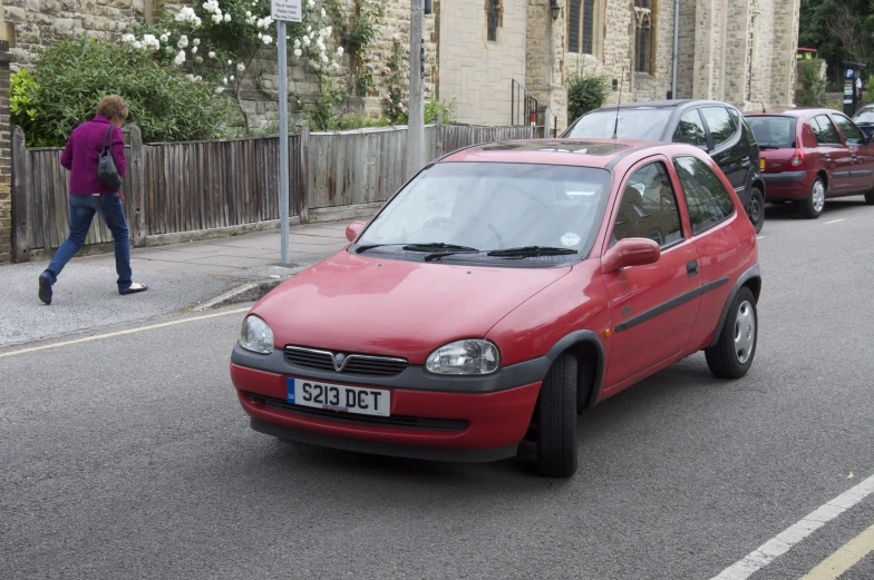 a red car sits parked in the middle of the road