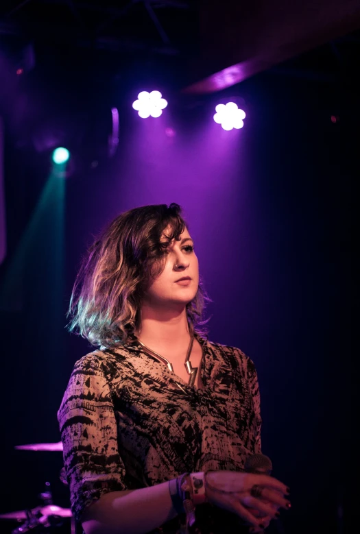 a woman standing in front of some spotlights on stage