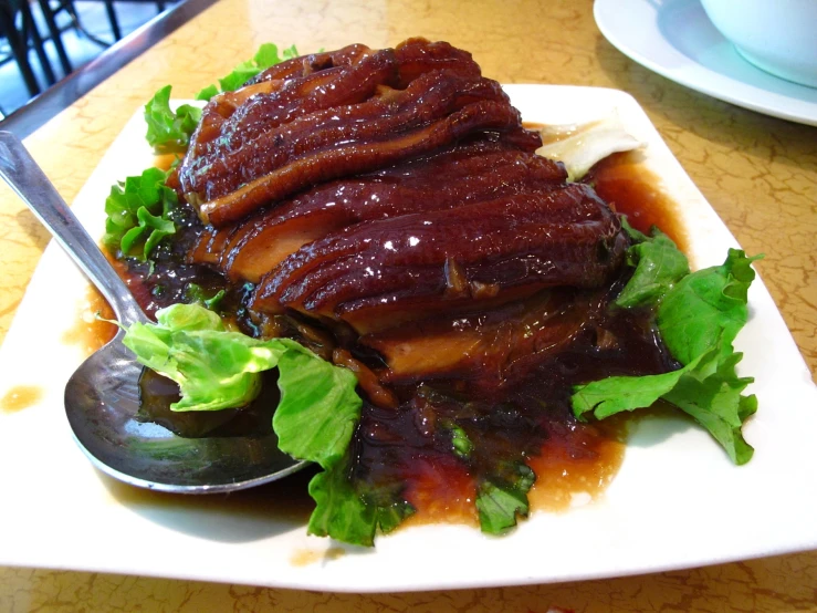 a plate topped with lettuce and meat with a spoon