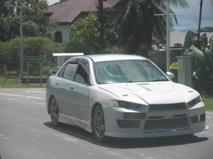 a white car driving on the street in front of palm trees