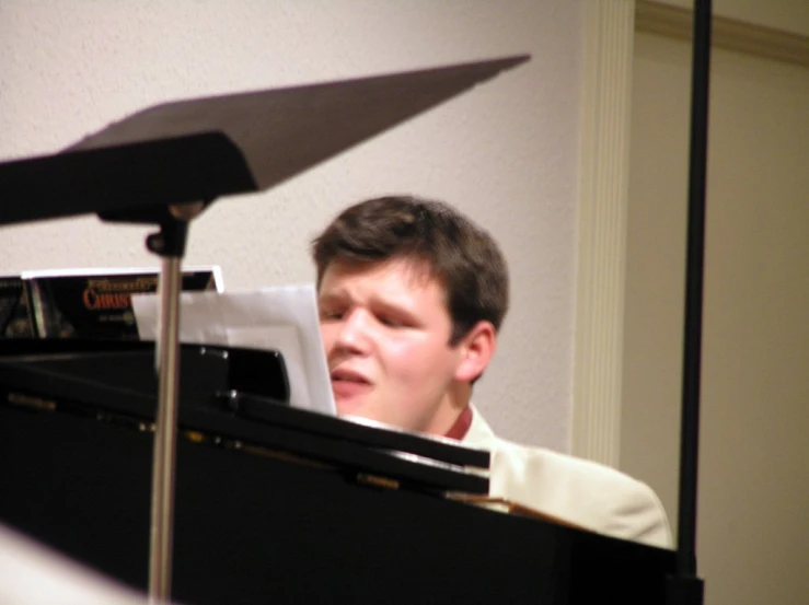 a boy sitting in front of a piano with a umbrella