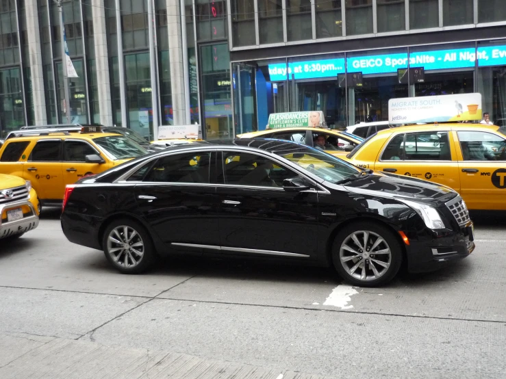 there is a car parked on the street next to yellow cabs