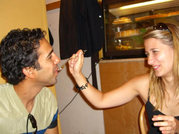 the man is sitting at a table feeding the woman soing