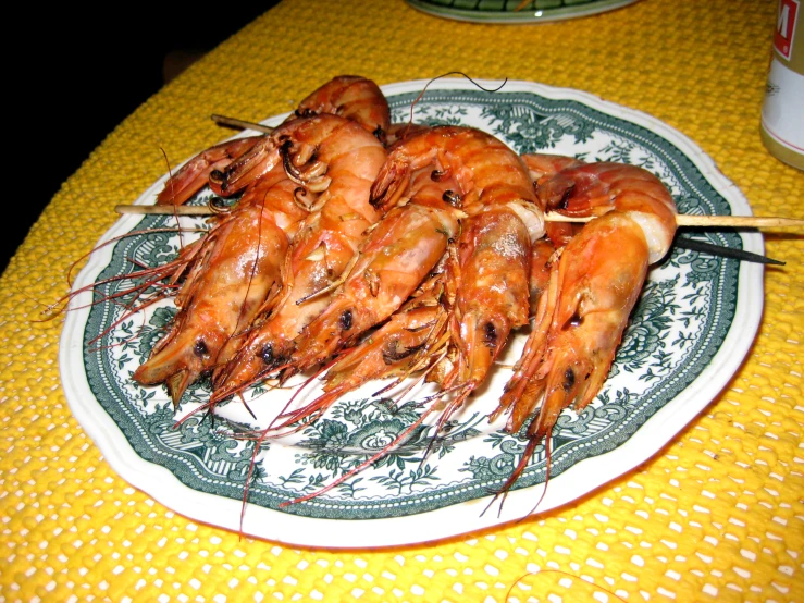 a white plate of shrimp with chopsticks sitting on a table