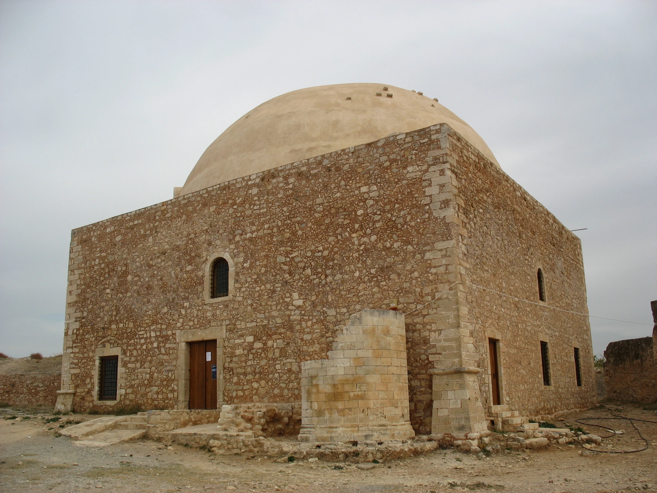 a round brick building surrounded by rubble and sand