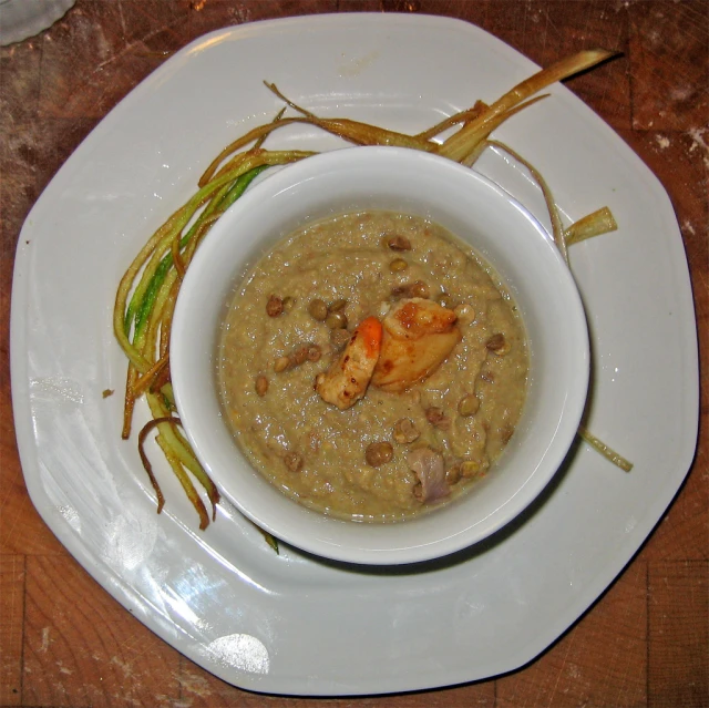 a bowl of brown color food sitting on top of a white plate