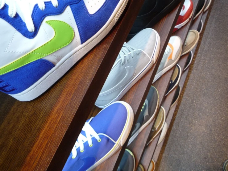pairs of shoes are lined up in a row on a wooden shelf
