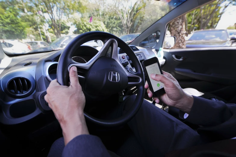 a person using a phone sitting in the driver seat of a car