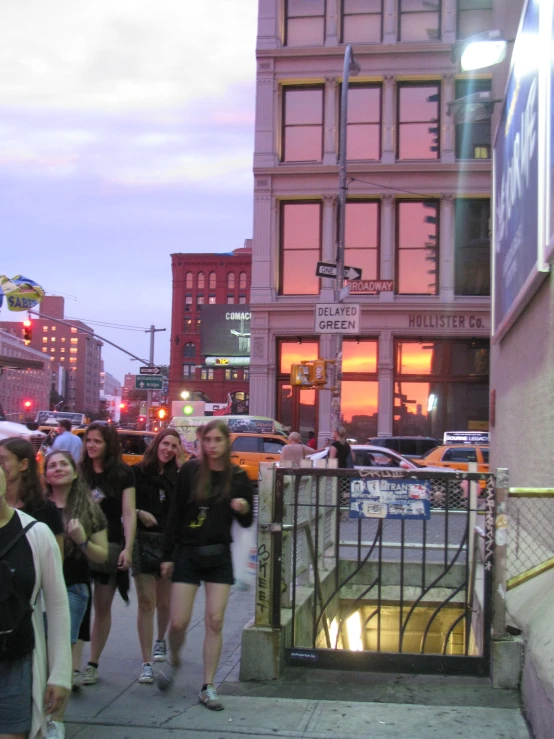 group of people walking down a city street at dusk