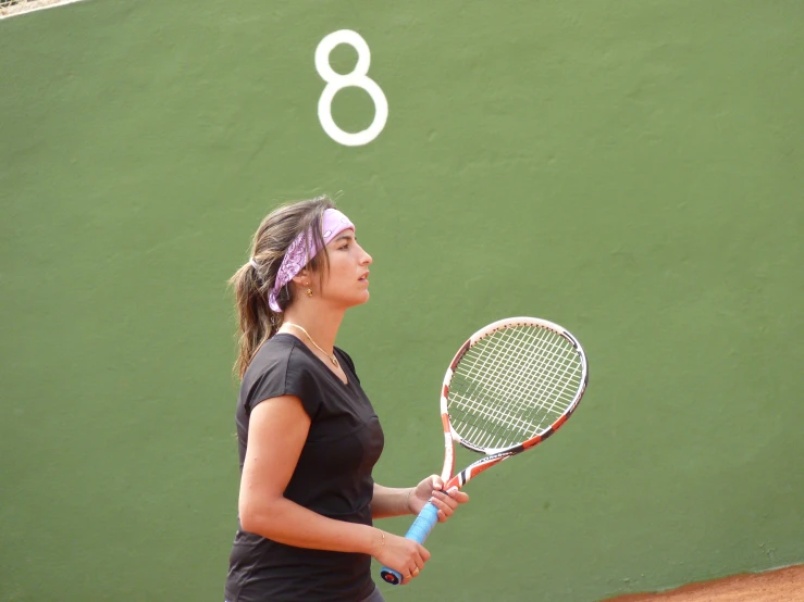 a woman holding a tennis racquet standing in front of a wall