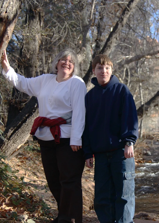 a young man and woman pose with their hands behind their back