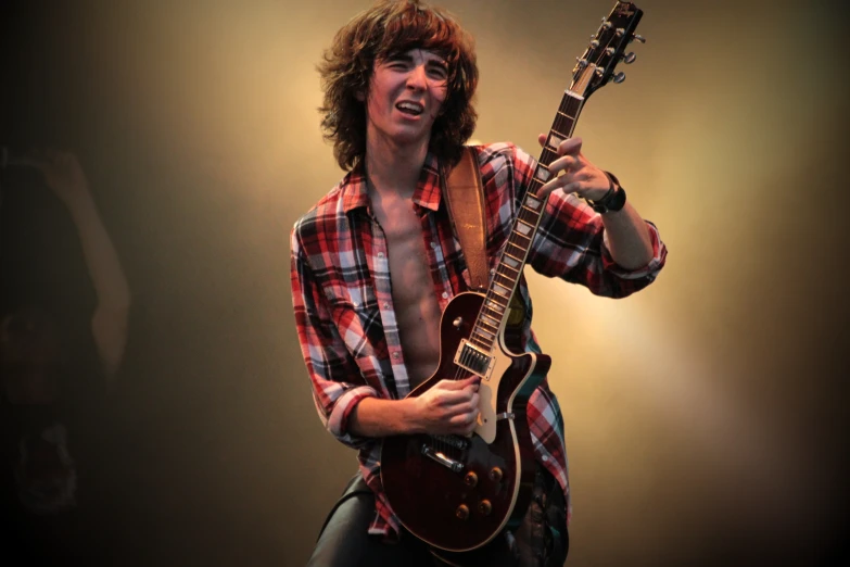 a young man playing an electric guitar in a stage setting