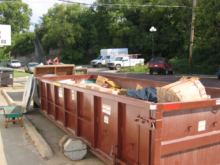 several dump cans and a truck in a lot with people on it