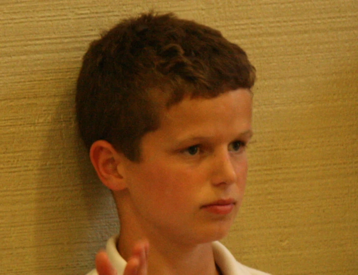a boy with brown hair is wearing white shirt