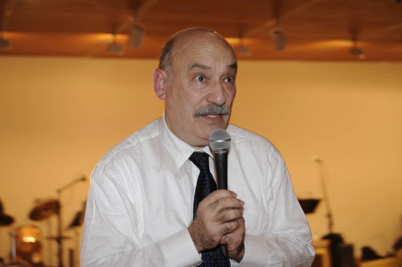 an older man wearing a tie and holding a microphone