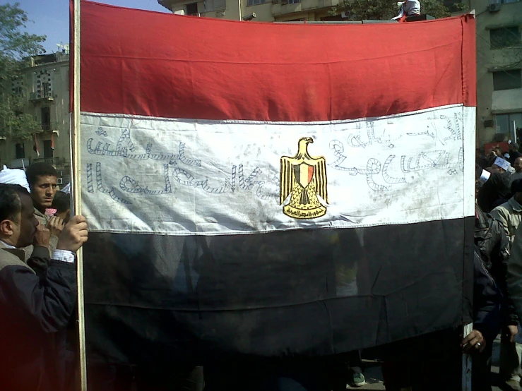 an egyptian man holds up a large flag