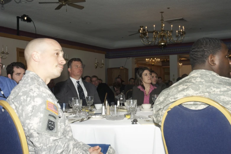 two men in uniform sit next to each other at a dinner table