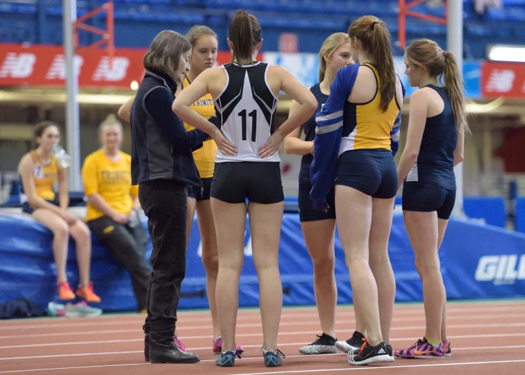 four girls in shorts on a track one girl is talking to the other