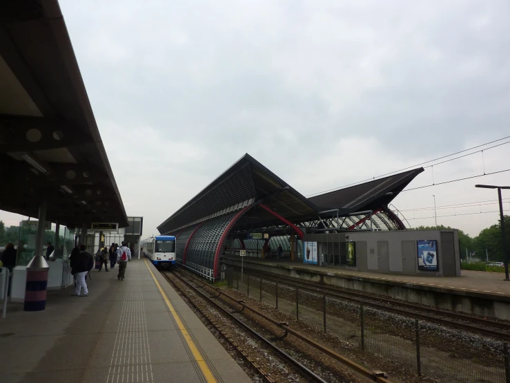 a train station with people waiting on the platform to get off