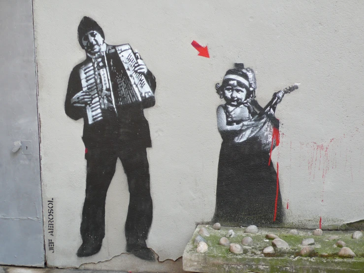 a street art depicting a man playing the accordion and a woman holding a red object