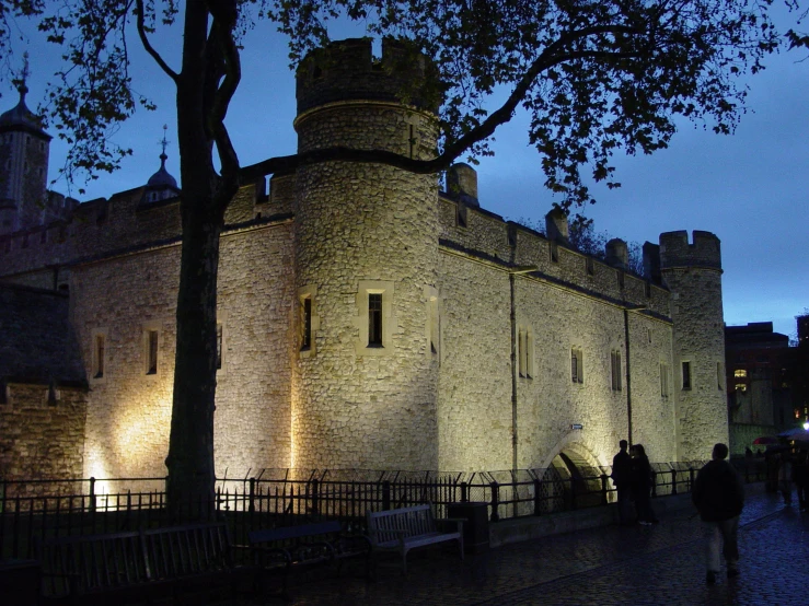 a white brick building that is at night with several people walking around