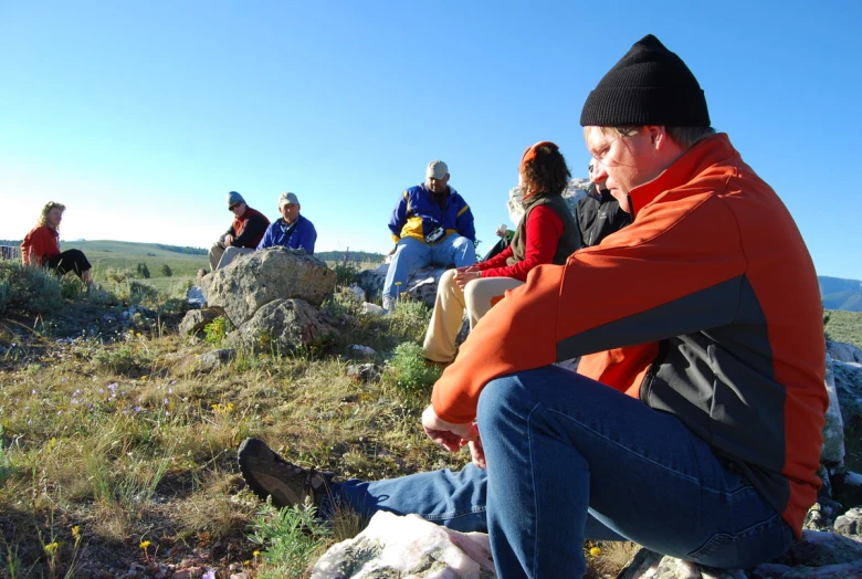 a group of people sit on the rocks and watch another people