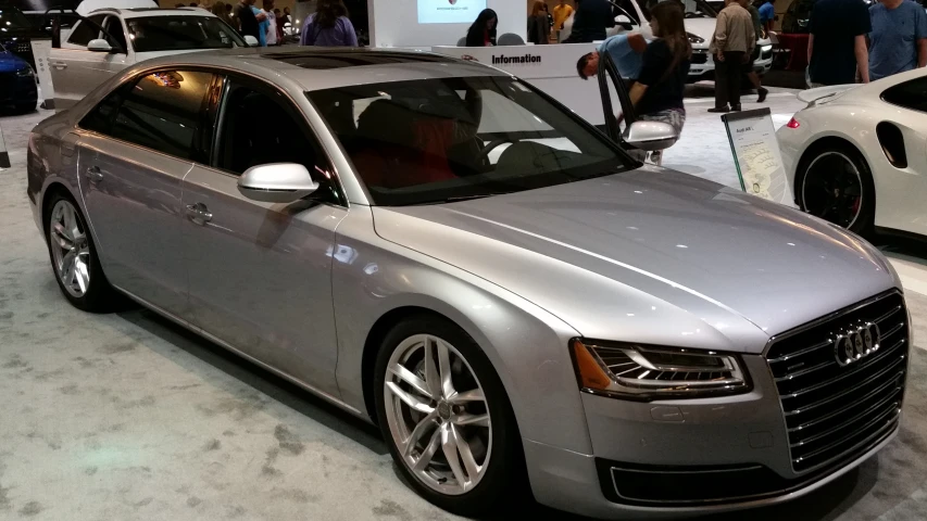 an audi car sits in a displayroom while others look at other cars