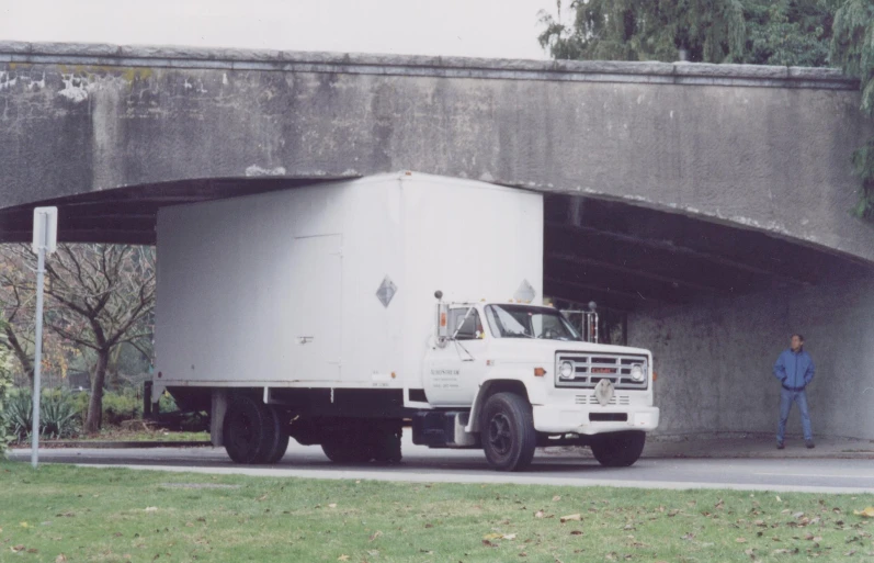 there is a large white truck that is parked under a bridge