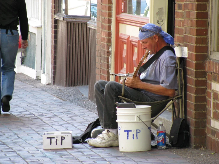 a street performer sits on a chair playing the flute